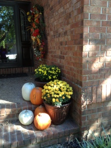 A few fake pumpkins and mums in pots at varying heights